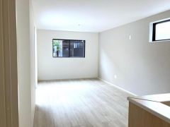 キッチン側からリビングを見渡すと、奥行きのある開放的な空間が広がります。天井のダウンライトが室内を均一に照らします。室内全体に視線が届くため、お子様がいる環境でも見守り可能