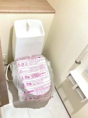 温水洗浄機能付きのトイレを採用しています。背面の棚は予備のトイレットペーパーや清掃用品の収納に便利です。ホワイトを基調とした内装で、清潔感のある空間です。